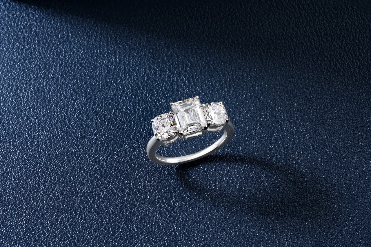 a three-stone engagement ring on a dark background