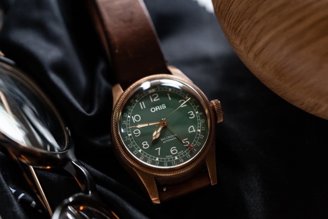 an Oris watch resting next to a pair of glasses