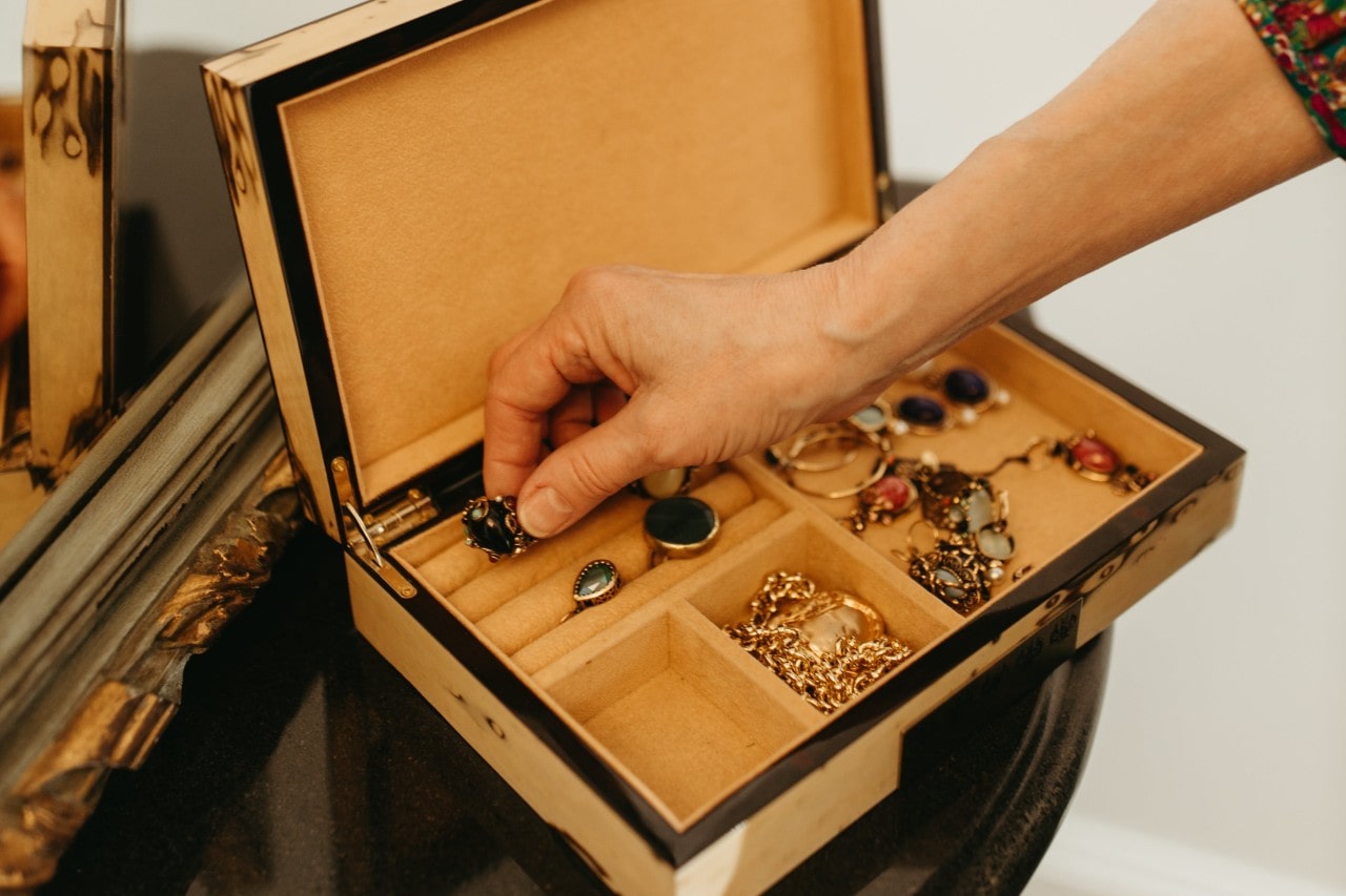 A woman taking an ornate ring out of a simple jewelry box.