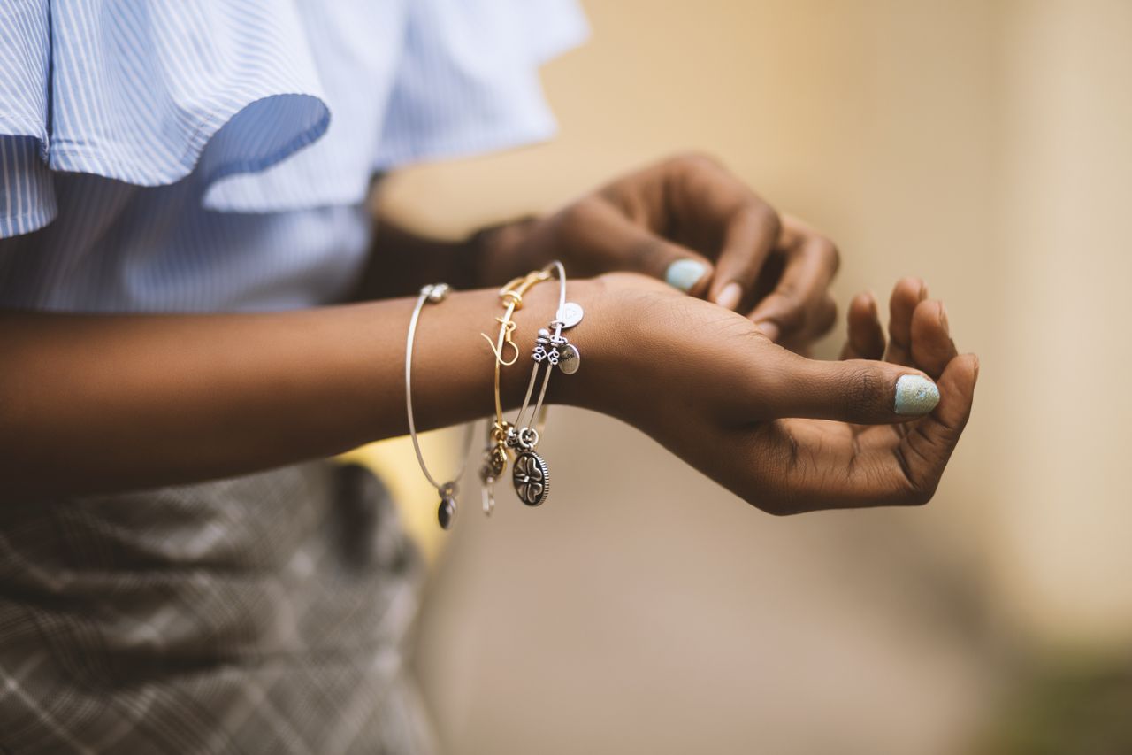 A close-up of a woman’s wrist, adorned with three delicate bracelets.