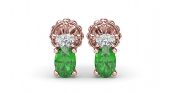 A rose gold pair of stud earrings, each featuring an oval cut diamond and emerald, available at Windsor Jewelers.