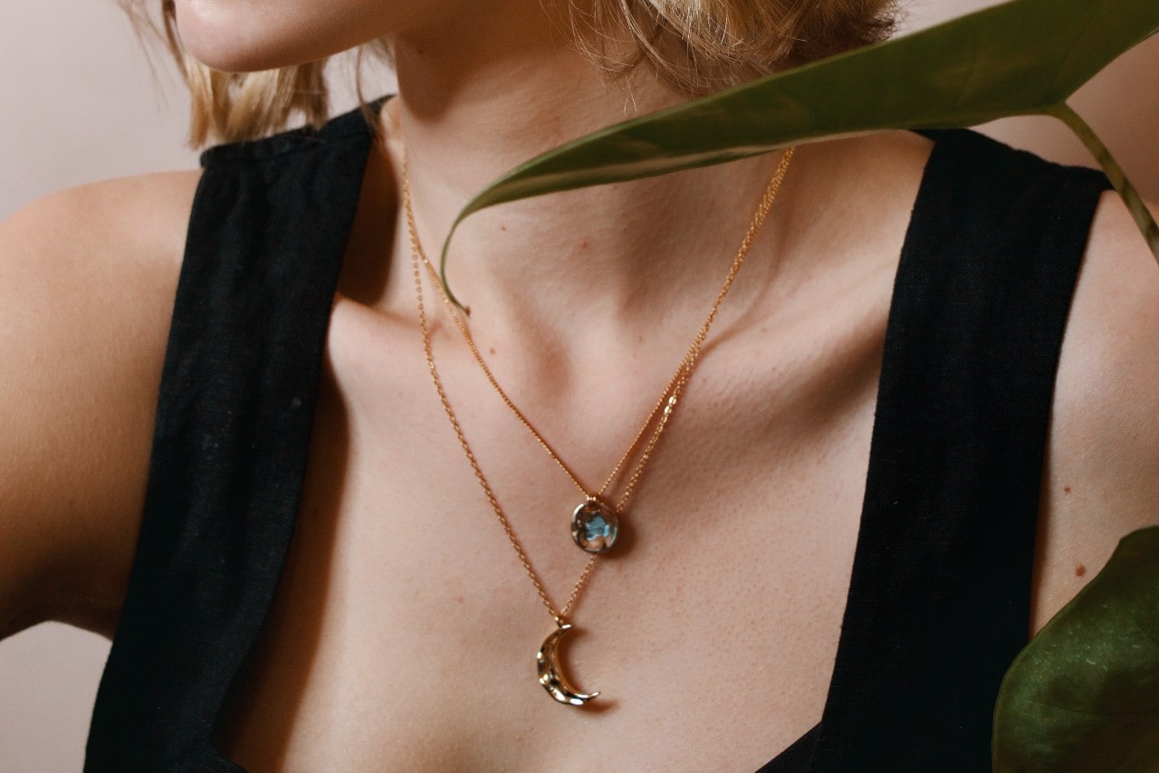 close up image of a woman’s neckline adorned with two yellow gold necklaces