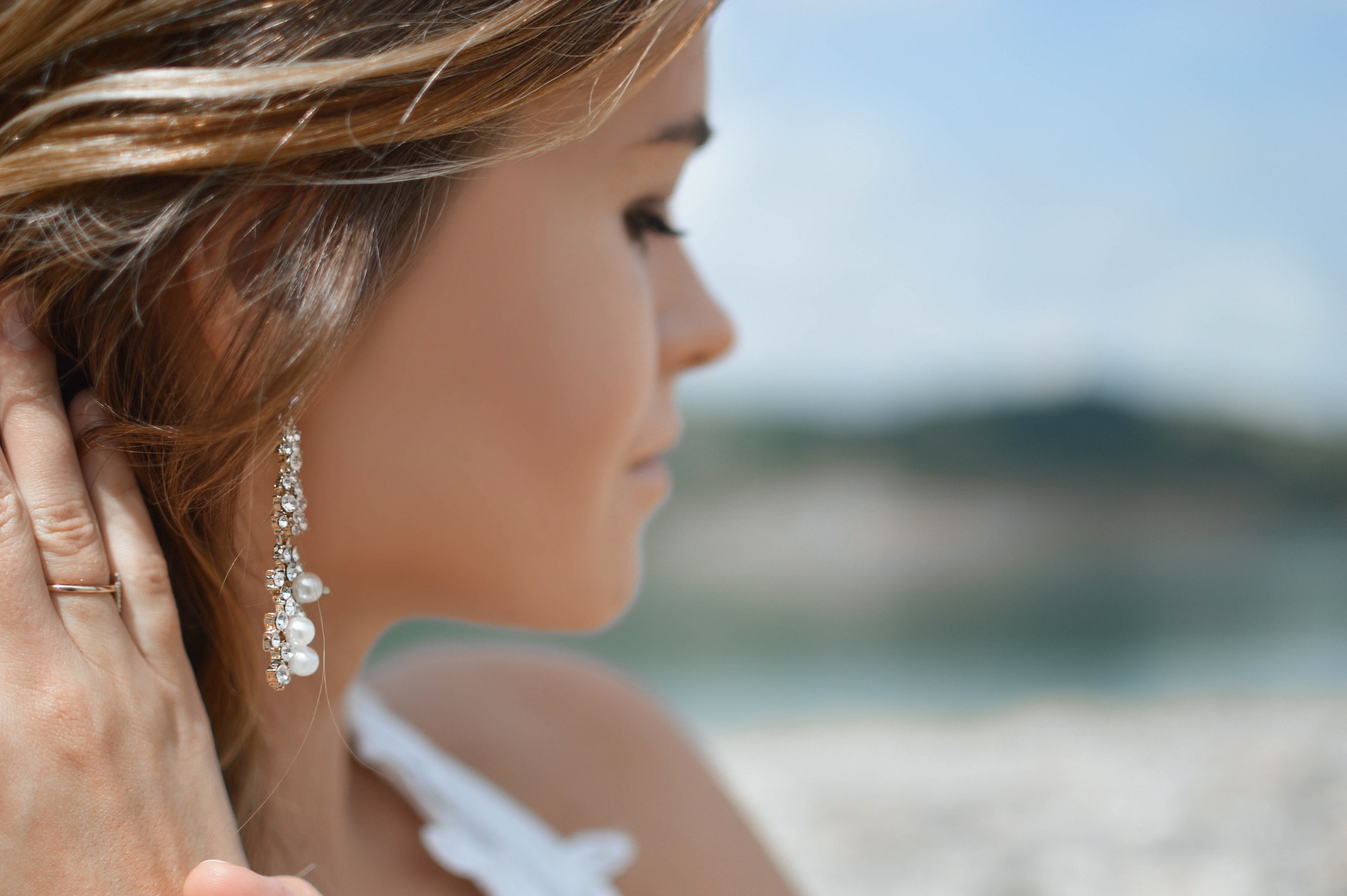 a woman looking away from the camera wearing a pair of drop earrings