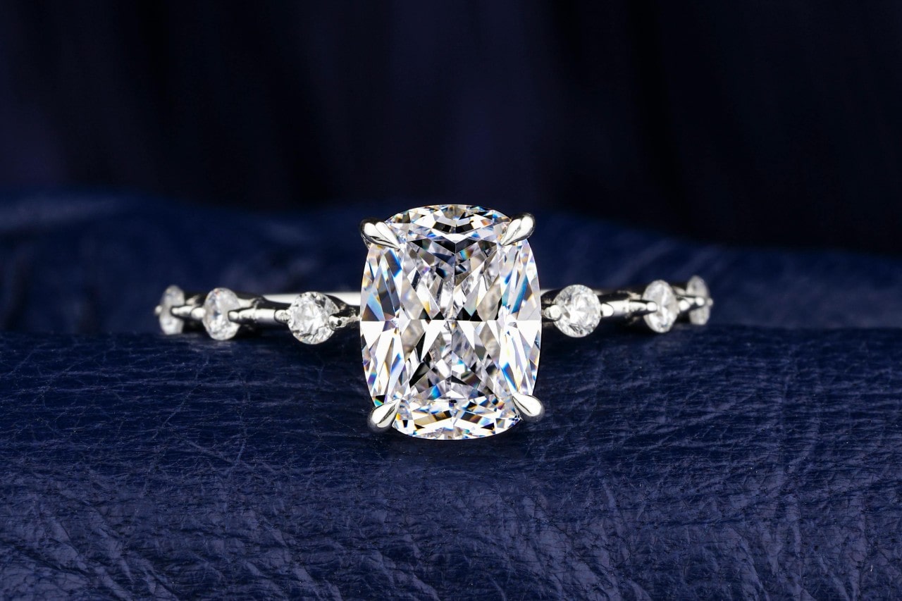 A close-up image of an engagement ring with a large center stone and round cut side stones.